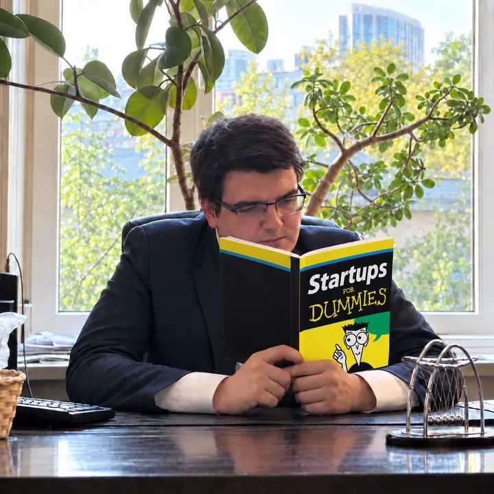 Alexander at his desk with an edited, satirical Startups for Dummies book cover